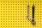 Two wrenches hang from hooks on yellow pegboard