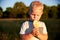 A two-year-old blonde boy eats a lollipop in a summer meadow