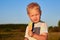 A two-year-old blonde boy eats a lollipop in a summer meadow