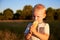 A two-year-old blonde boy eats a lollipop in a summer meadow