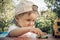 A two year old boy rolls a small toy car on a table outdoors. A child plays with small cars on a summer day.