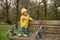 Two year old boy in yellow raincoat and welly boots playing