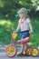 Two year-old standing near pink and yellow kids tricycle with steel frame