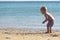 Two years blonde baby picking, collecting, playing and counting sea shells in hand at golden sand beach sea shore