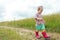 Two years old preschooler girl walking by foot on farm field summer dirt road