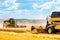 Two yellow combines harvest wheat in the field. Farm grain harvest.