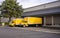 Two yellow different small rigs semi trucks with box trailers standing in warehouse dock and loading cargo for the next local