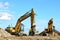 Two yellow excavators at a construction site. Excavator with crusher bucket for crushing concrete.