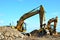 Two yellow excavators at a construction site. Excavator with crusher bucket for crushing concrete.