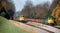 two yellow and green trains passing each other on train tracks