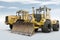 Two yellow heavy wheeled tractors isolated on bright background