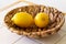 Two yellow lemons in rope bowl on white ceramic table and wooden and white background