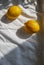 two yellow lemons on a white cloth with folds in sunlight