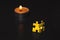 Two yellow puzzles standing against a candle.