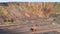 Two Yellow Quarry Trucks One Behind Another are Driving on a Dusty road