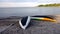 Two yellow, white and green canoes placed upside down on the beach to dry after a row