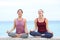 Two yogis laughing doing yoga on the beach