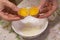 Two yolks in one egg. 2 in 1. Women`s hands open a unique egg with two yolks. The process of opening eggs for making cake,