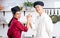 Two young adult Asian professional couple chefs wearing uniform, hat, happily smiling with confidence, happiness, giving high five