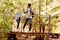 Two young adult friends hiking in a forest crossing a footbridge, full length