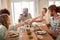 Two young adult women passing a dish across the dinner table during lunch with friends, close up