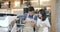 Two young asian barista man and woman using tablet computer during a break on the work in the coffee shop