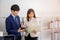 Two young Asian businessmen stand meeting in the office in the hand of the tablet