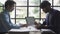 Two young asian businessmen in suits discussing financial market data in office Business team working