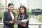 Two young Asian businesswomen looking into document file folder for analyzing profit or sale break even point after marketing.