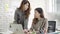 Two young Asian businesswomen working together in office at small business sitting reading a report or paperwork with pleased.