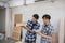 Two young asian carpenters holding wooden job sample and notebook in workplace