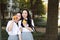 Two young Asian Chinese pretty girls wear student suit in school best friends smile laugh smell orange fruit in nature