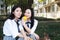 Two young Asian Chinese pretty girls wear student suit in school best friends smile laugh smell orange fruit in nature