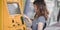 Two young asian female withdrawing the money from a bank card using ATM machine