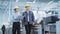 Two Young Asian Heavy Industry Engineers in Hard Hats Walking with Laptop Computer and Discussing