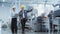 Two Young Asian Heavy Industry Engineers in Hard Hats Walking with Laptop Computer and Talking in a