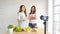 Two young asian women healthy food bloggers talking while recording video with happy moment, vlog concept, people and technology