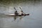 Two young athletes are sailing canoe on river, controlling oars. Active outdoor sports training. Back view. Copy space.