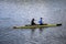 Two young athletes are sailing canoe on river, controlling oars. Active outdoor sports training. Copy space.