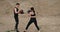 Two Young Athletes Wearing Black Sportswear and Boxers Equipment, Man Teaching Woman Kickboxing, Healthy Lifestyle and