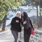 Two young attractive women in dark autumn clothes walking along park