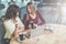 Two young attractive women sit at round wooden table in cafe, drinking coffee and talking. Business meeting.