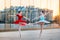 Two young ballerinas in a bright red and blue tutu are dancing against backdrop of the reflection of city sunset