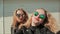 Two young beautiful girlfriends blonde in sun glasses on her face fun and coquettish posing in front of the camera. Do