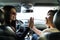 Two young beautiful girls traveling by car giving five palms facing each other despite the road