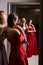 Two young beautiful girls wearing off-the-shoulder full-length sky blue and crimson red satin slit prom ball gowns