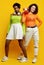 Two young beautiful hipster girls in trendy colorful summer clothes