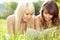 Two young beautiful smiling women reading book