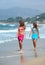 Two young beautiful tanned women walking along sandy beach