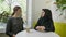 Two young beautiful womans sitting in cafe, one of them muslim woman in hijab telling something to other woman